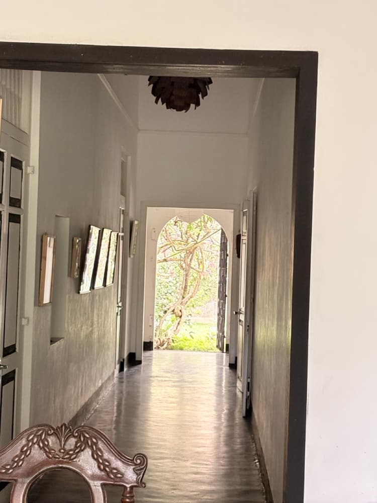Long shaded corridor inside the house leading to a bright arched doorway opening onto the garden