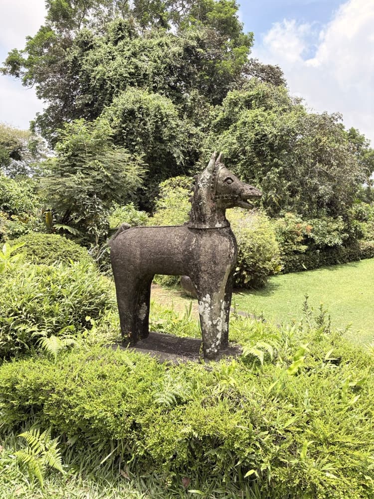 Life-size weathered stone horse standing on a clipped lawn