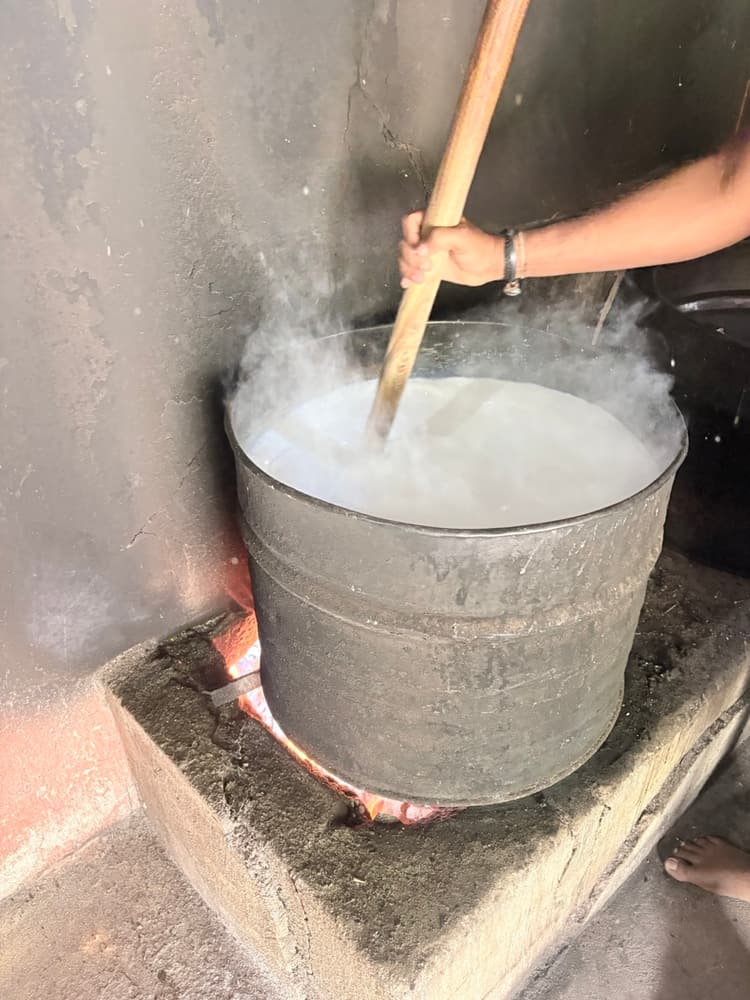 Buffalo milk boiling in a large pot over a wood fire at a roadside curd maker near Kantale