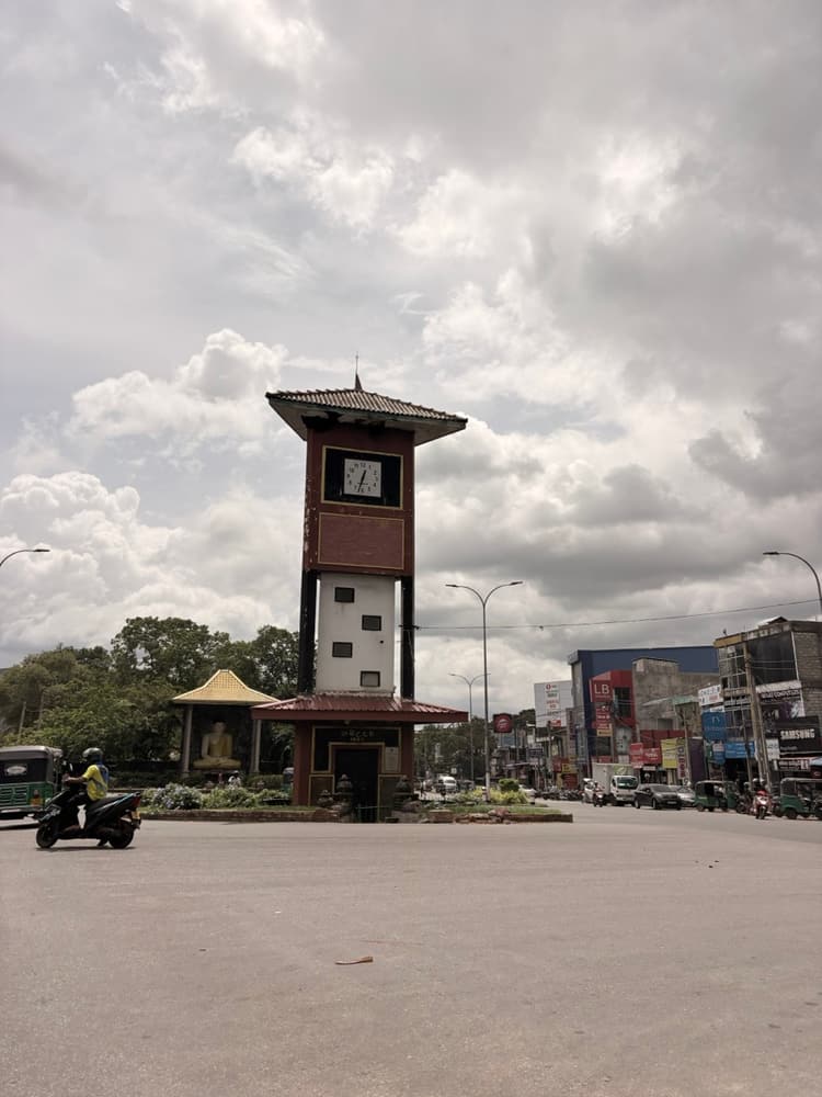 Clock tower roundabout in the centre of Dambulla town with shops behind