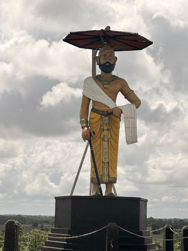 Statue of King Aggabodhi II, the builder of Kantale tank, standing under a parasol on the tank bund