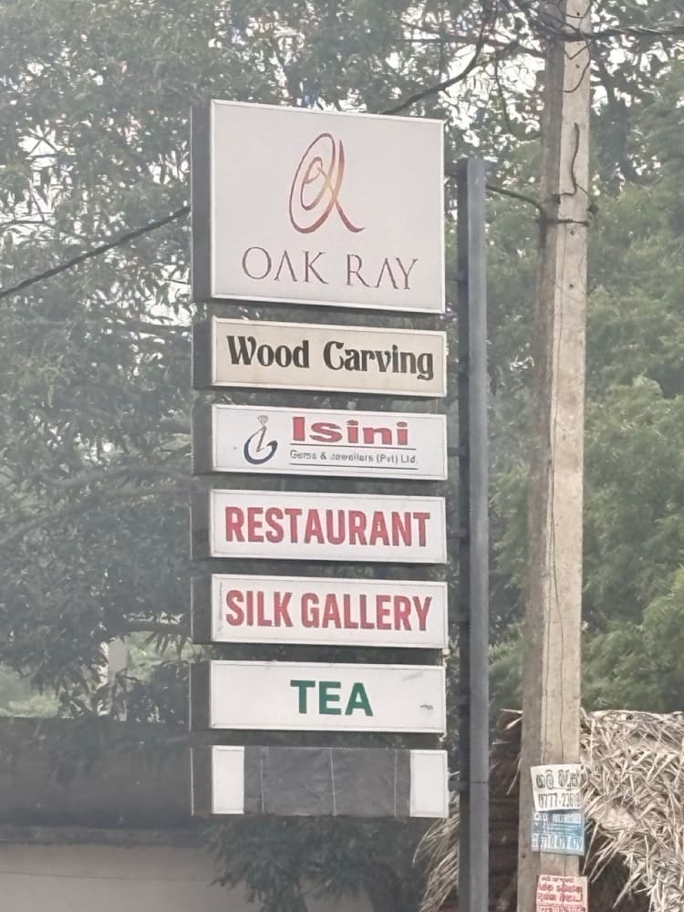 Roadside sign for Oak Ray listing wood carving, gems, a restaurant, a silk gallery and tea