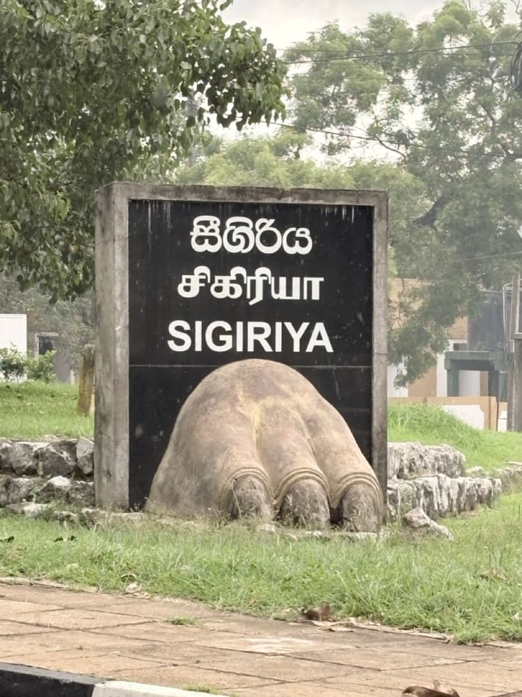 Sigiriya sign in Sinhala, Tamil and English with a stone lion's paw at Inamaluwa junction on the Trincomalee road