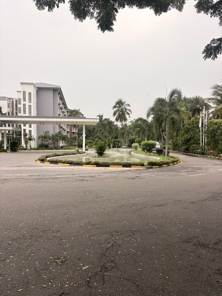 Fountain roundabout at the hotel entrance with palm trees and a room wing behind