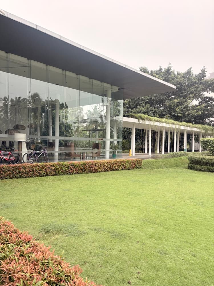 Lawn and clipped hedges in front of the glass lobby building at Vivanta Colombo Airport Garden