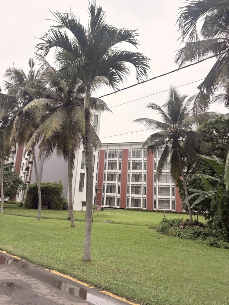 Room wing of Vivanta Colombo Airport Garden behind a wide lawn and tall palm trees